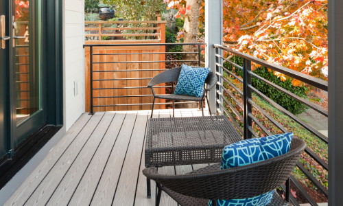 An outdoor deck with composite decking and black railing surrounded by fall foliage
