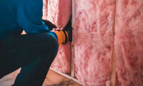 Pink insulation being installed to a wall