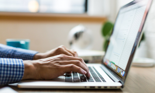 A close up of hands typing on a laptop